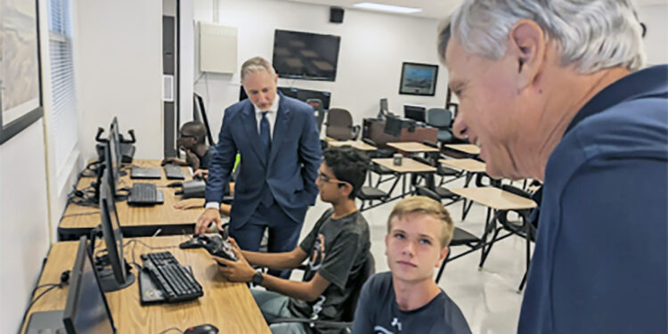 SRHS NJROTC Cadets Devon Desai (seated left) and Preston Kross (seated right) discuss the benefits of flight simulator software with Peter Petrelis (far right) and Jay Rinchak (far left).