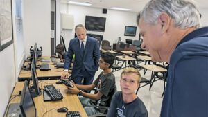 SRHS NJROTC Cadets Devon Desai (seated left) and Preston Kross (seated right) discuss the benefits of flight simulator software with Peter Petrelis (far right) and Jay Rinchak (far left).